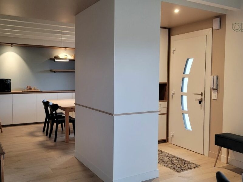 Une porte d'entrée, un espace entrée avec des rangements, un espace repas dans lequel on devine une table et des chaises. Un architecture d'intérieur repensée par Oll Design.