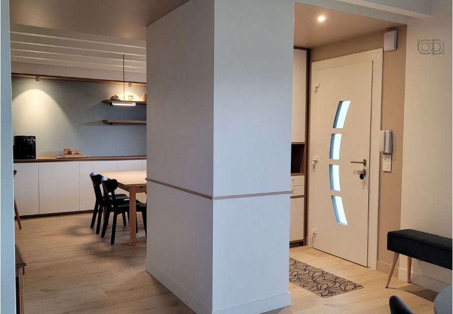 Une porte d'entrée, un espace entrée avec des rangements, un espace repas dans lequel on devine une table et des chaises. Un architecture d'intérieur repensée par Oll Design.